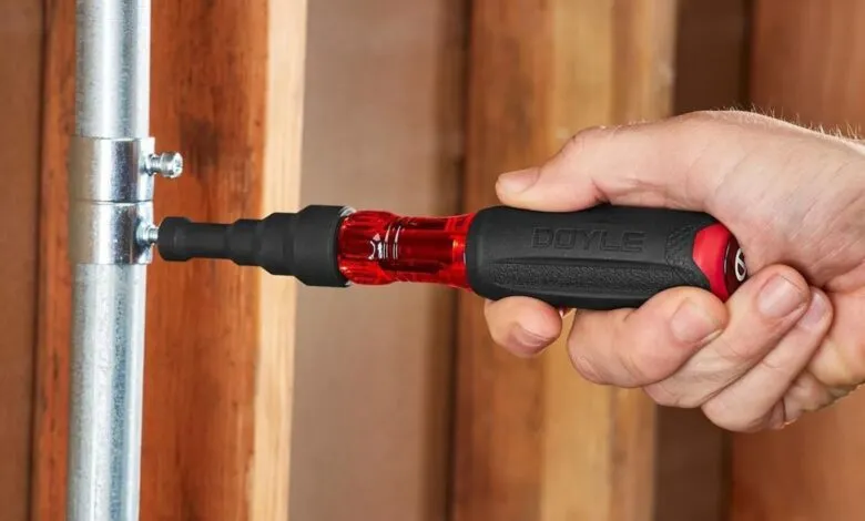 Hand tightens metal pipe fitting with Doyle screwdriver.