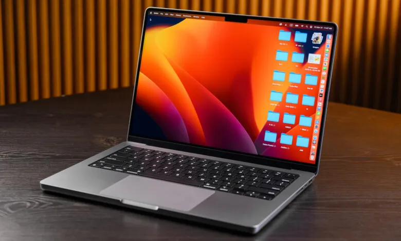 Open MacBook Pro on a wooden desk showing a desktop with folders.