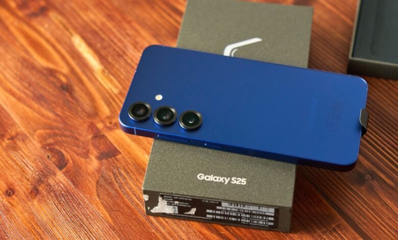 Blue Samsung Galaxy S25 rests on its box on a wooden surface.