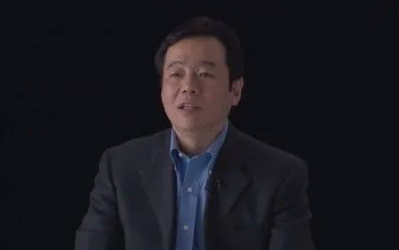Portrait of a man in a suit against a black background.