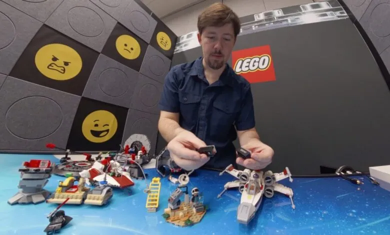 Man holds LEGO smart bricks surrounded by LEGO Star Wars sets.