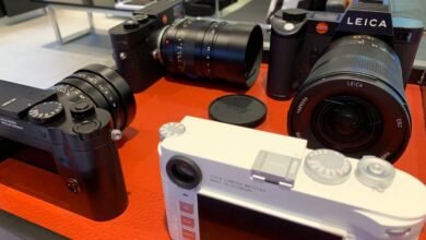 Several Leica cameras and lenses displayed on a red surface.