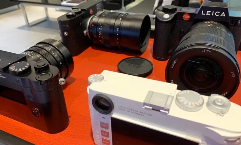 Several Leica cameras and lenses displayed on a red surface.