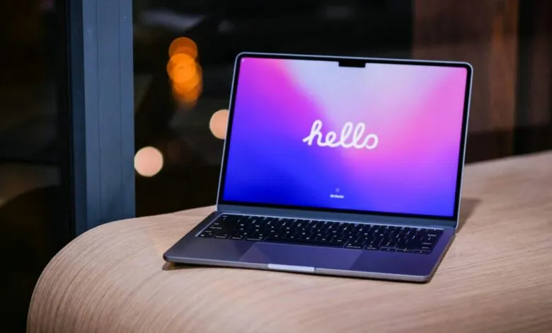 New MacBook Air with 'hello' displayed on a vibrant purple and pink screen.