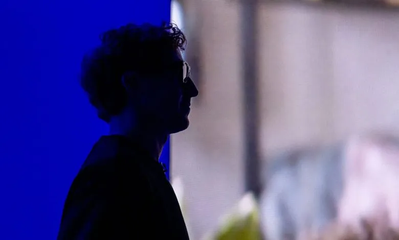 Silhouette of a person with glasses against a blue and blurred background.