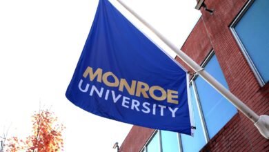 Monroe University flag waving outside a brick building.