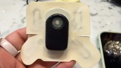 Close-up of a wearable sensor patch held in a hand.