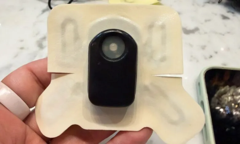Close-up of a wearable sensor patch held in a hand.