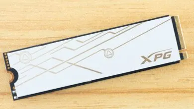XPG M.2 NVMe SSD with white heatsink and gold accents on wood surface.