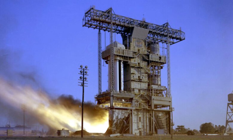 Rocket engine test stand firing with flames and smoke.