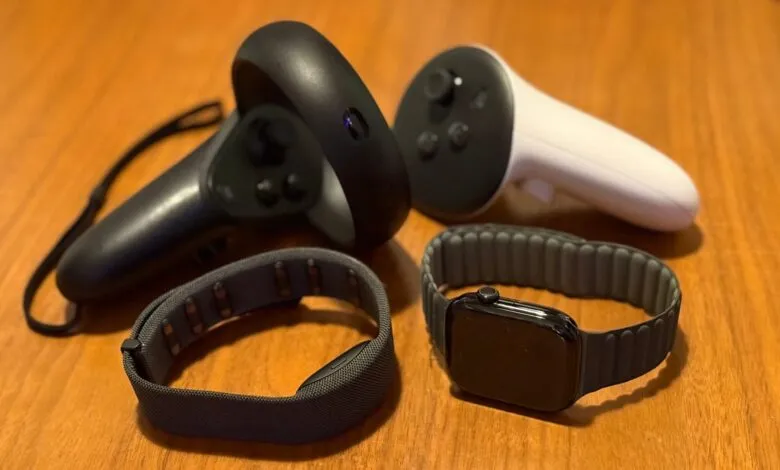 VR controllers, Apple Watch, and fitness band on a wooden surface.