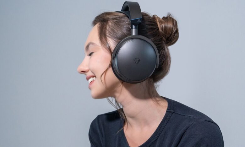 Woman with brown hair in a bun wearing black over-ear headphones, smiling.