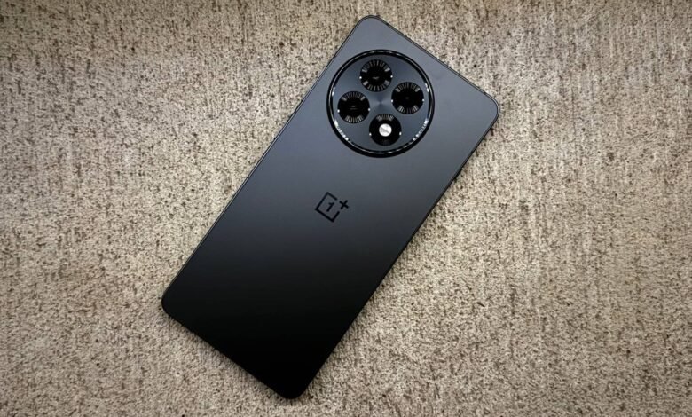 Black OnePlus phone with circular camera array on textured surface.