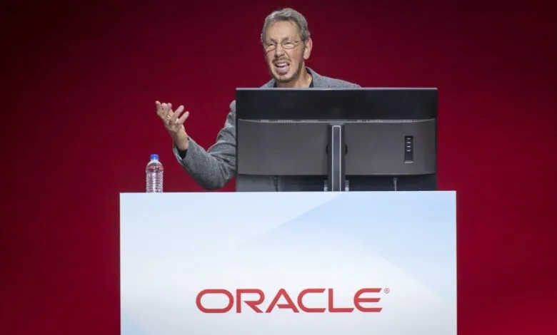 Larry Ellison speaks at Oracle event, gesturing with hand.