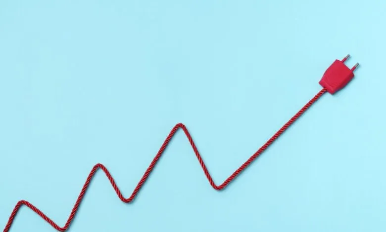 Red power plug and cord form an upward trending chart on blue.