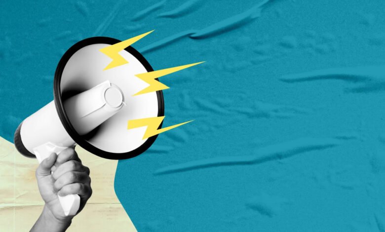 Hand holding megaphone with lightning bolts on blue textured background.