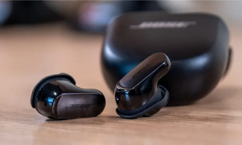 Bose QuietComfort Earbuds II and charging case on a wooden surface.