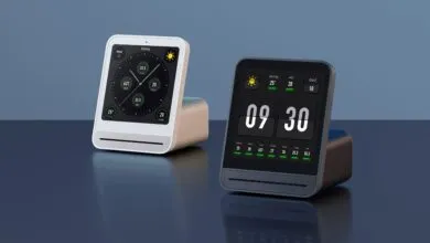 Two Qingping air quality monitors, one white and one black, display time and air quality data.