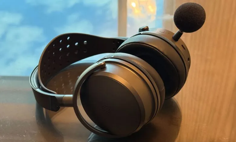Close-up of black gaming headset with microphone on reflective surface.