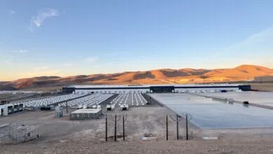Large energy storage facility with rows of batteries and a long warehouse building.