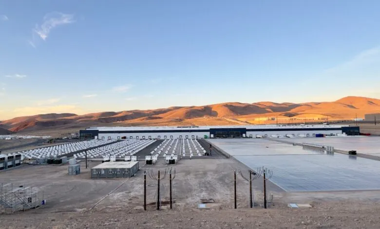 Large energy storage facility with rows of batteries and a long warehouse building.
