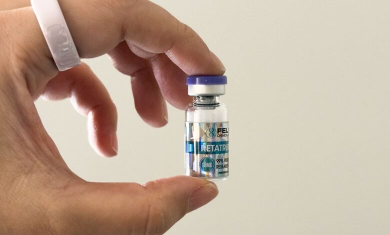 Hand holds vial labeled Retatrutide, a research chemical.