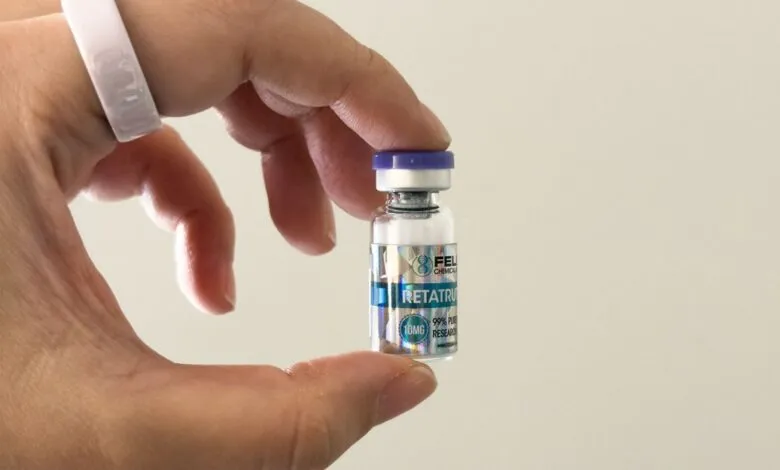 Hand holds vial labeled Retatrutide, a research chemical.