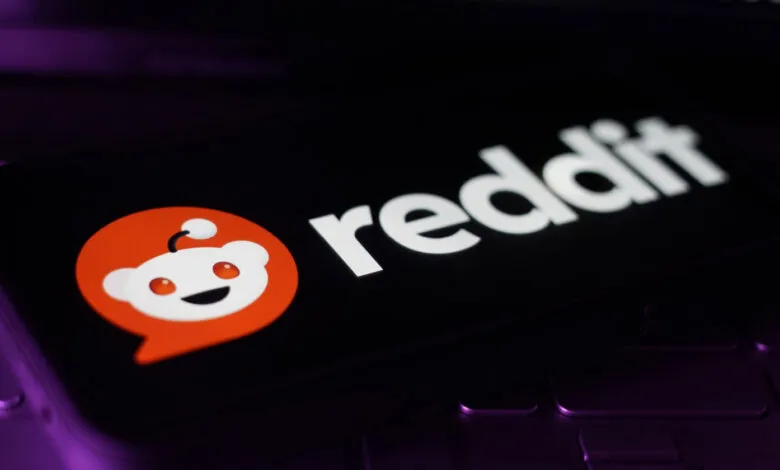 Reddit app logo displayed on a smartphone screen, resting on a laptop keyboard.