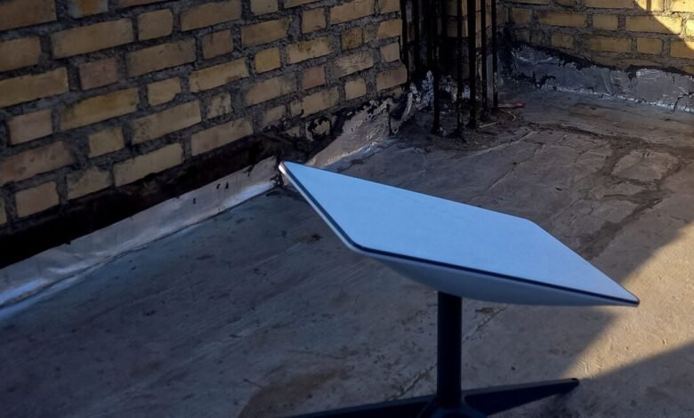 Starlink receiver on rooftop with brick wall backdrop.