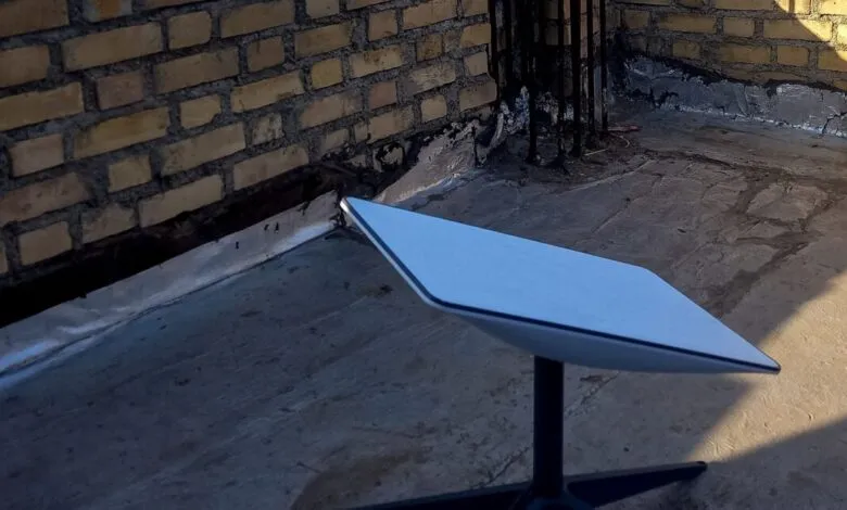 Starlink receiver on rooftop with brick wall backdrop.