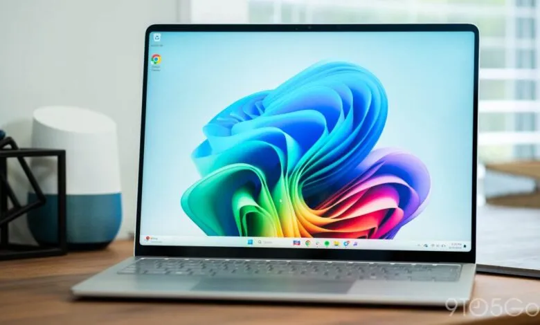 Silver laptop on a wooden desk displaying a colorful, abstract wallpaper.