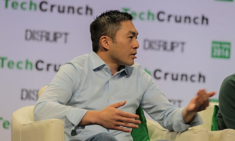 Man in light blue shirt speaking at TechCrunch Disrupt event.
