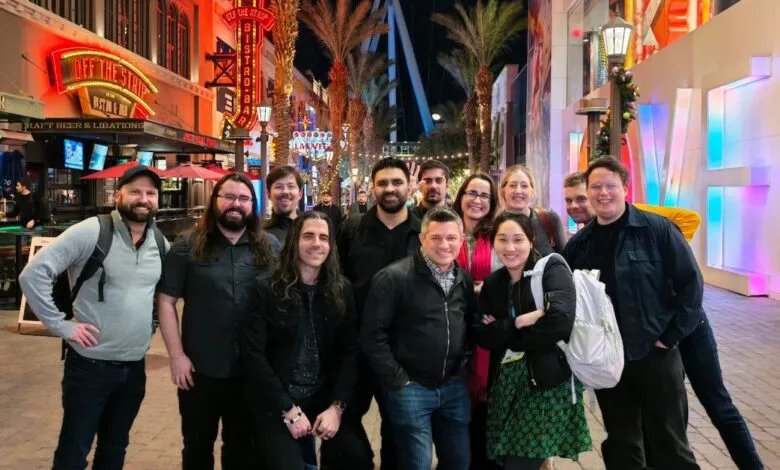 Group of about a dozen people posing for a photo on a city street at night.