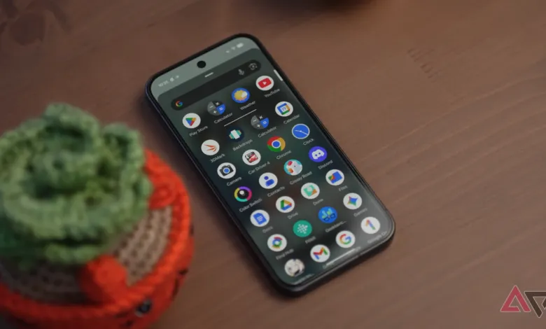 Smartphone displaying app icons on a wooden surface with a small plant.