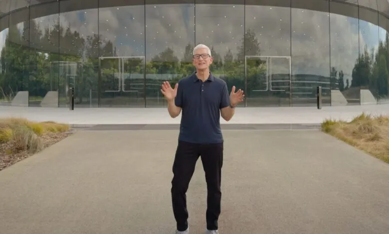 Tim Cook stands outside Apple Park with hands raised in a welcoming gesture.