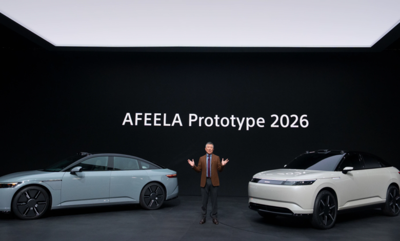 A man stands between two AFEELA Prototype 2026 electric vehicles on a stage.