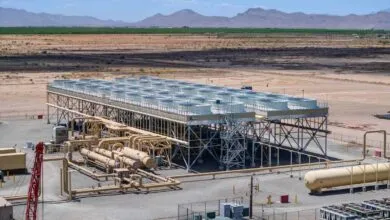 Industrial facility with cooling towers and pipeline infrastructure in desert landscape.