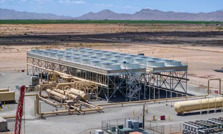 Industrial facility with cooling towers and pipeline infrastructure in desert landscape.
