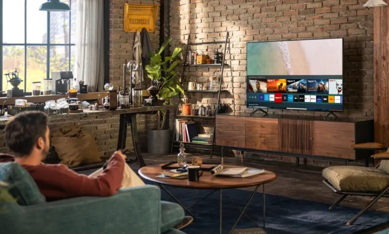 Man relaxes in living room with brick wall, watching TV.