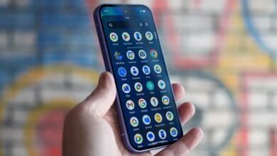 Hand holding a smartphone displaying the Google Pixel home screen.