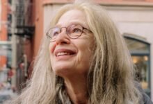 Laurie Spiegel, musician, looks up with a smile in an urban setting.