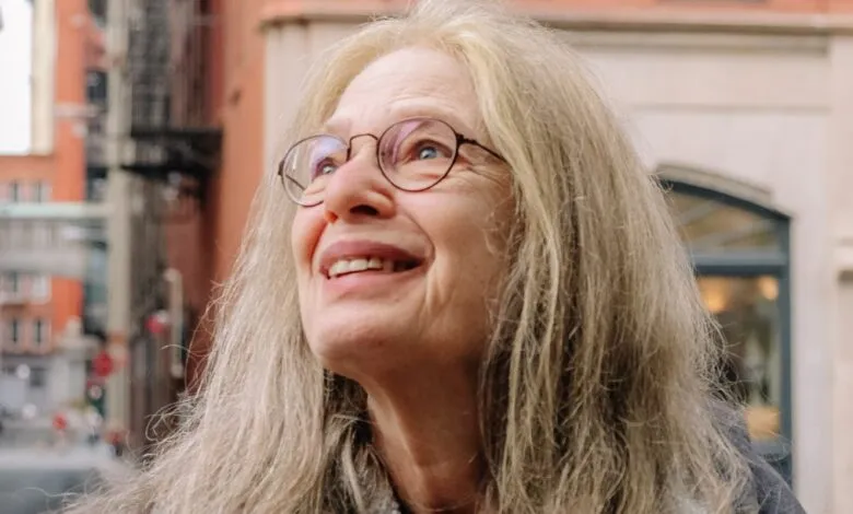 Laurie Spiegel, musician, looks up with a smile in an urban setting.