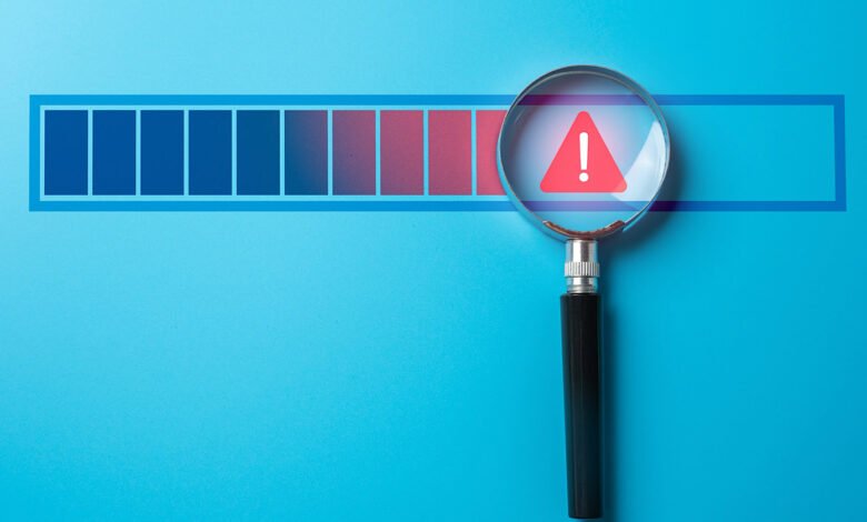 Magnifying glass over progress bar with a warning sign.