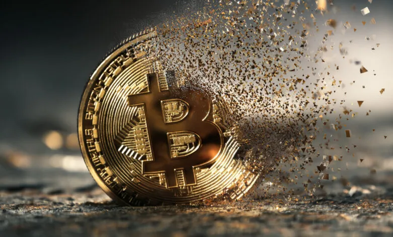 Golden Bitcoin coin disintegrating into small particles on a textured surface.