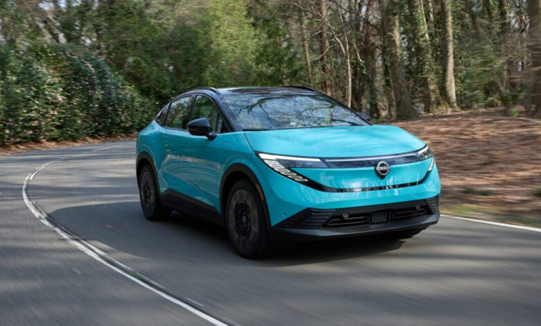 Teal Nissan Leaf electric car driving on a winding road.