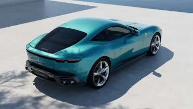 Rear view of a teal Ferrari Amalfi sports car parked on a light gray surface.