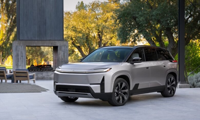 Silver Toyota bZ4X SUV parked outside with modern fireplace.