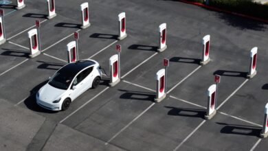 Aerial view of a white Tesla charging at a Tesla Supercharger station.