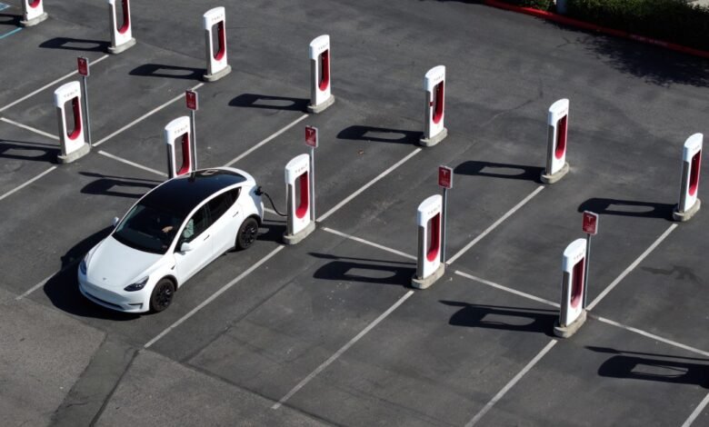 Aerial view of a white Tesla charging at a Tesla Supercharger station.