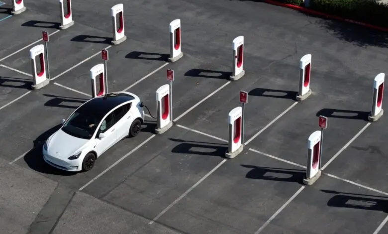 Aerial view of a white Tesla charging at a Tesla Supercharger station.